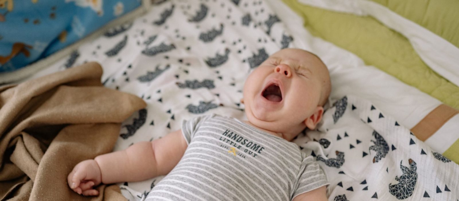 Gapende baby ligt op een dekentje
